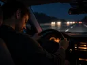 Übermüdeter Autofahrer mit gesenktem Kopf am Steuer bei Nacht auf der Autobahn